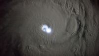 An aerial photo of the eye of a cyclone illuminated by a lightning strike