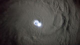 An aerial photo of the eye of a cyclone illuminated by a lightning strike