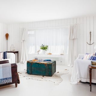 white coastal living room with white curtains and wooden chest