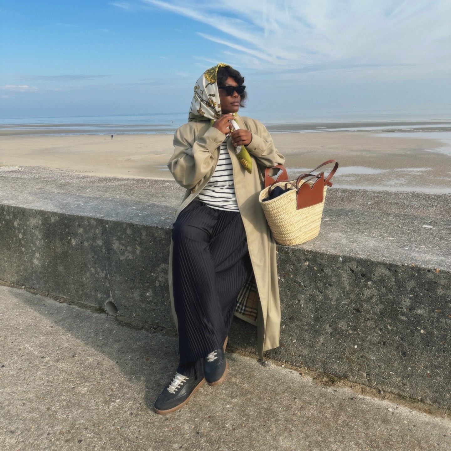Photo of Franny Fyne sitting at the beach wearing a headscarf
