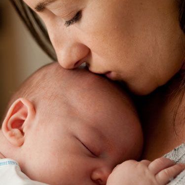 mother holding and kissing baby