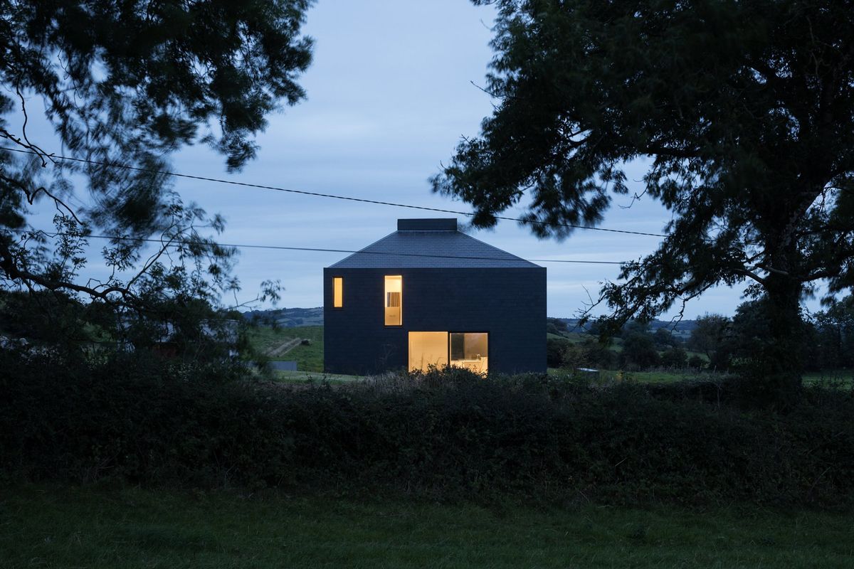 A square shaped home with black tiles at nighttime