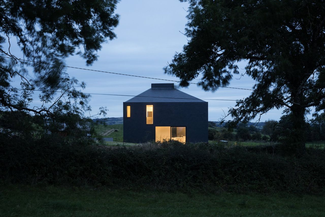 A square shaped home with black tiles at nighttime