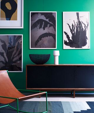 A bold green living room with leather chair and tribal style artwork.