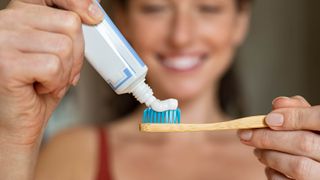 A woman applying toothpaste to a toothbrush