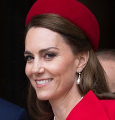 Kate Middleton wearing a red coat and hat and smiling at the camera on Commonwealth Day 2025