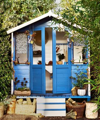blue painted shed raised from the ground with wood pile outside