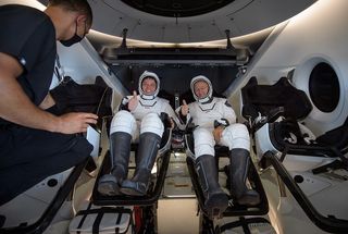 NASA astronauts Bob Behnken (left) and Doug Hurley give thumbs-up signs inside the SpaceX Crew Dragon Endeavour onboard the GO Navigator recovery ship shortly after having landed in the Gulf of Mexico off the coast of Pensacola, Florida on Aug. 2, 2020. 