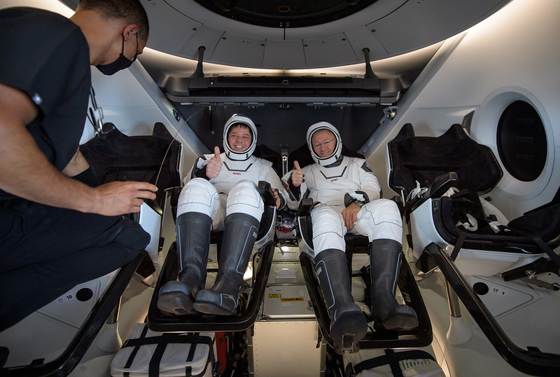 Dos astronautas uno al lado del otro en asientos Crew Dragon