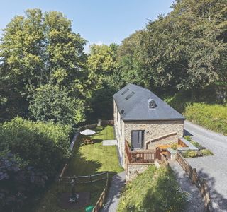 A converted barn in a rural setting with a fenced lawn and gravel walkway