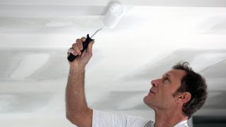 A man painting the ceiling with a roller