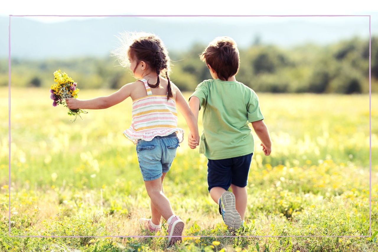 A young boy and girl holding hands while running through a field