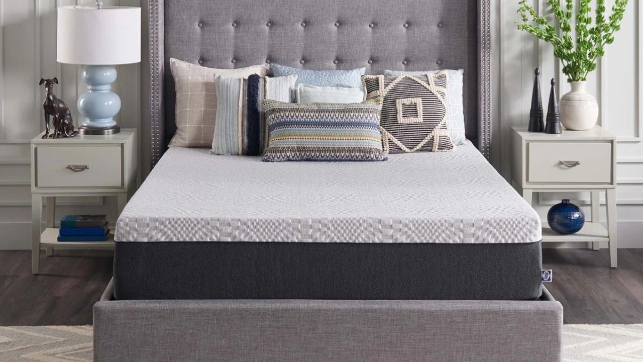 the Sealy Cool Memory Foam mattress on a grey bedframe with multiple cushions on top