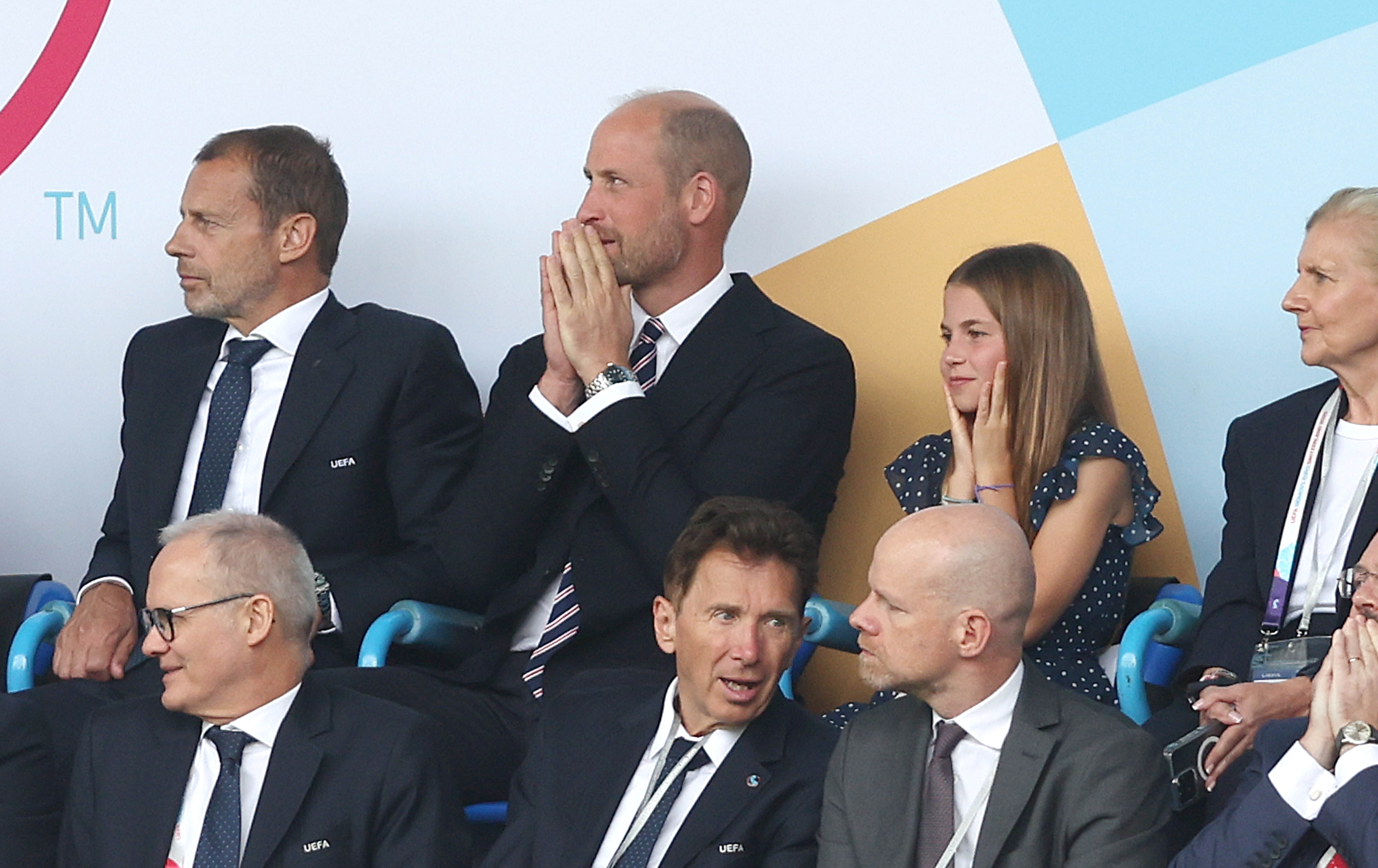 Prince William and Princess Charlotte with their hands on their faces at a soccer match