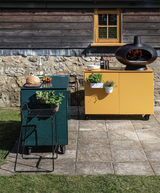 A set of freestanding modular kitchen units in green and mustard colorways in backyard