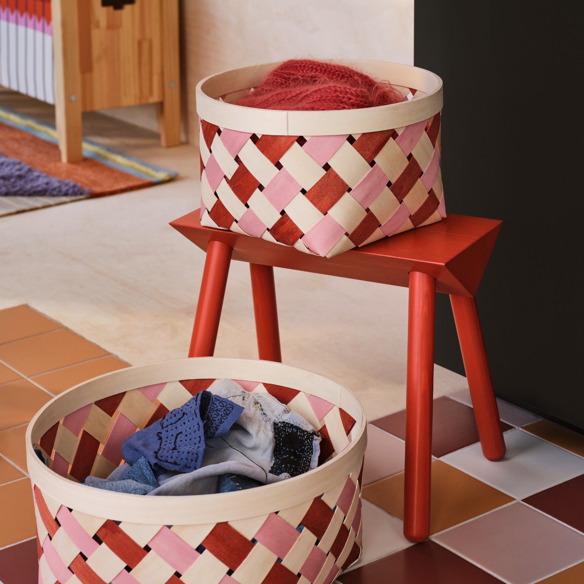 A red stool with two two-tone storage baskets from the IKEA OMMJ&amp;Auml;NGE range