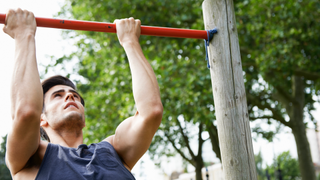 Man doing a pull-up whilst working out outdoors