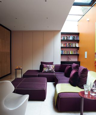 Decorating small spaces in a modern living room with large purple sectional and sky light.