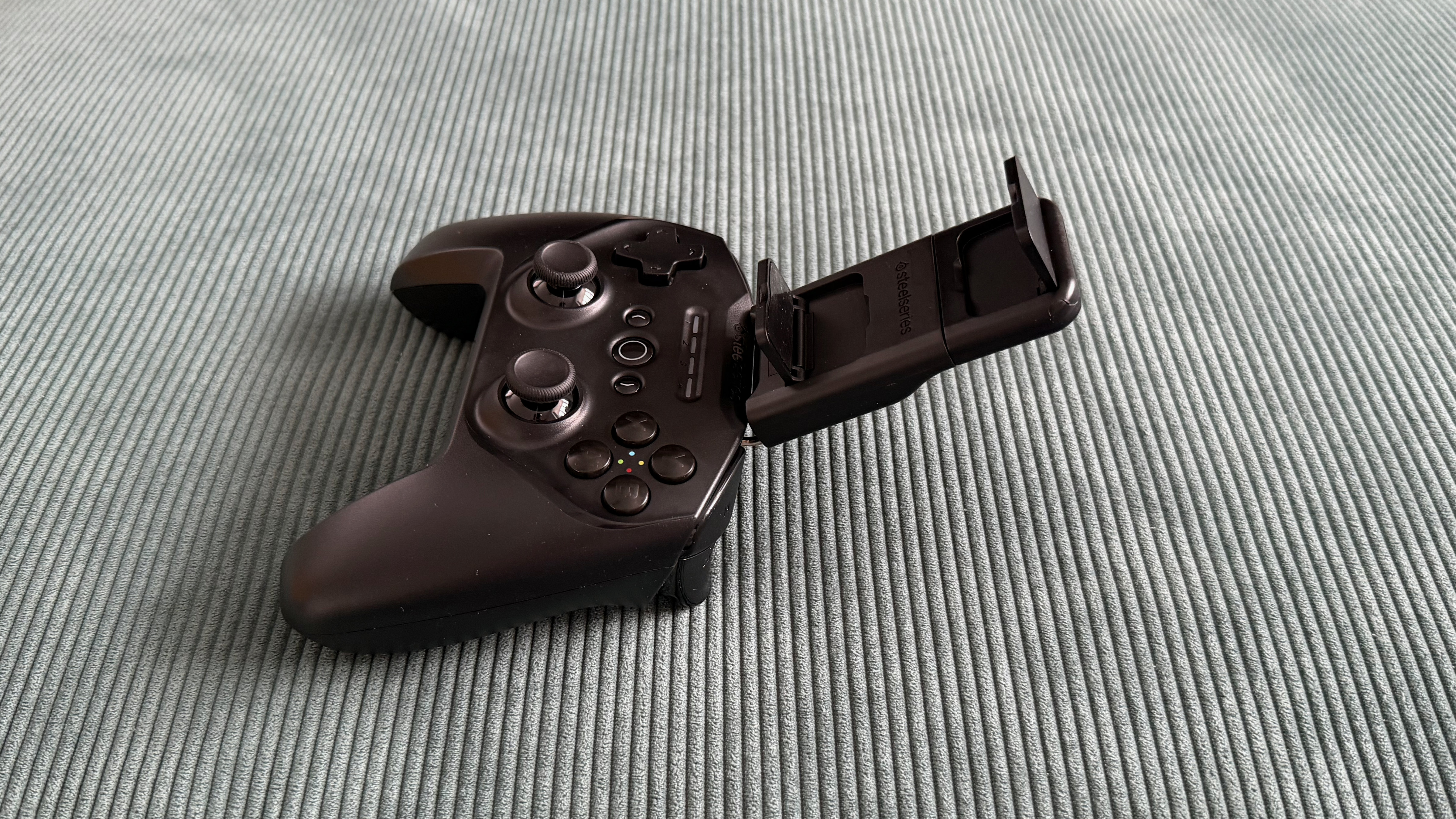 The SteelSeries Stratus+ mobile and PC controller on top of a green carpet surface