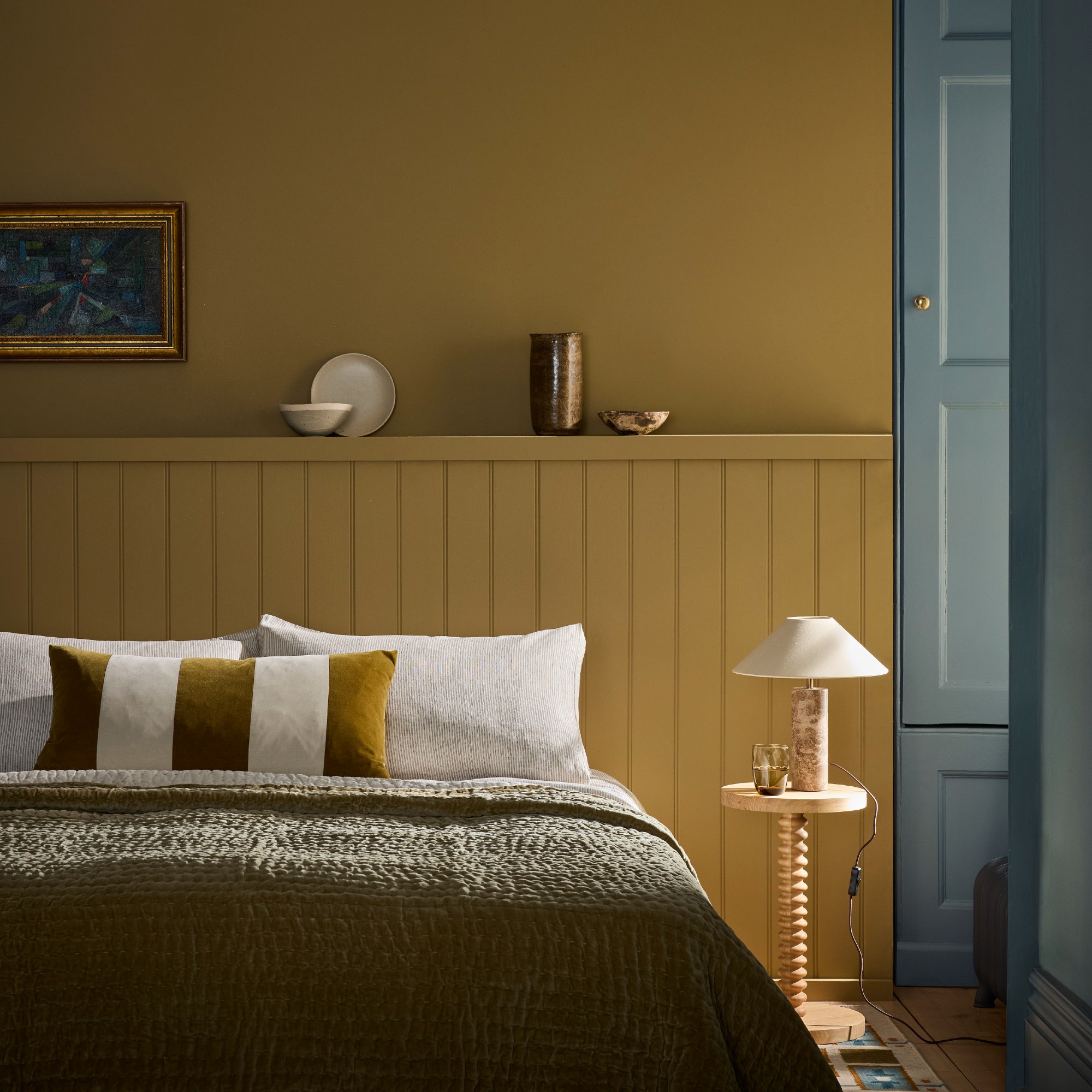 A bedroom painted in Little Greene's new Elysian Yellow shade on the wall and Perpetual Blue on the window shutters