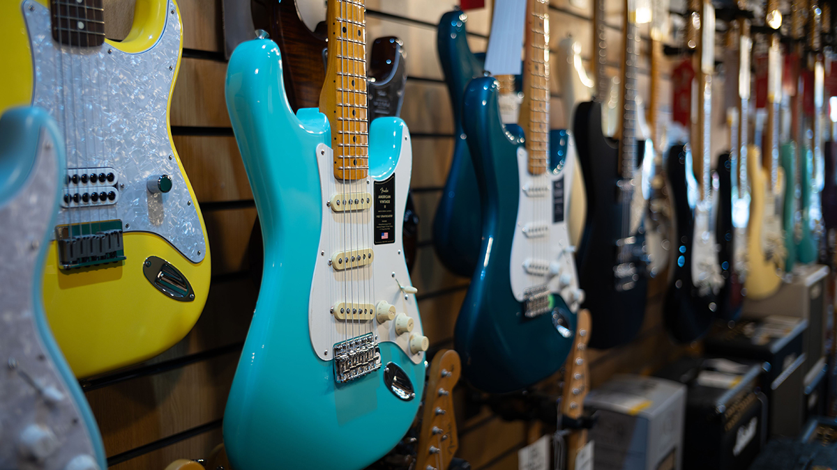 A turquoise Fender American Vintage II electric guitar hanging with other electric guitars for sale in Gak Music Emporium in Brighton, East Sussex, UK