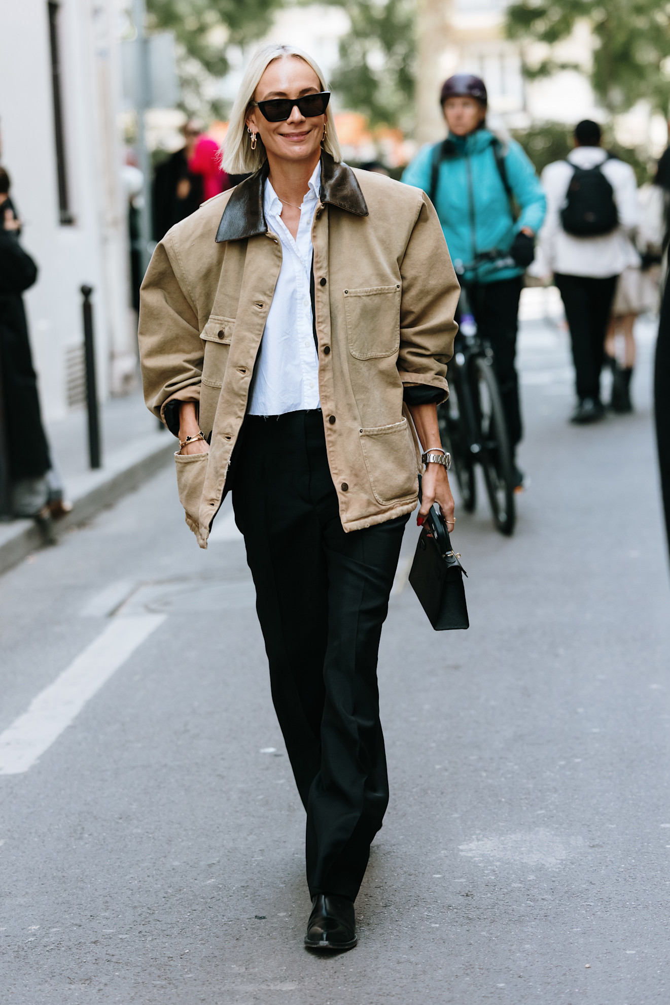 woman wearing barn jacket, white button down, and black pants