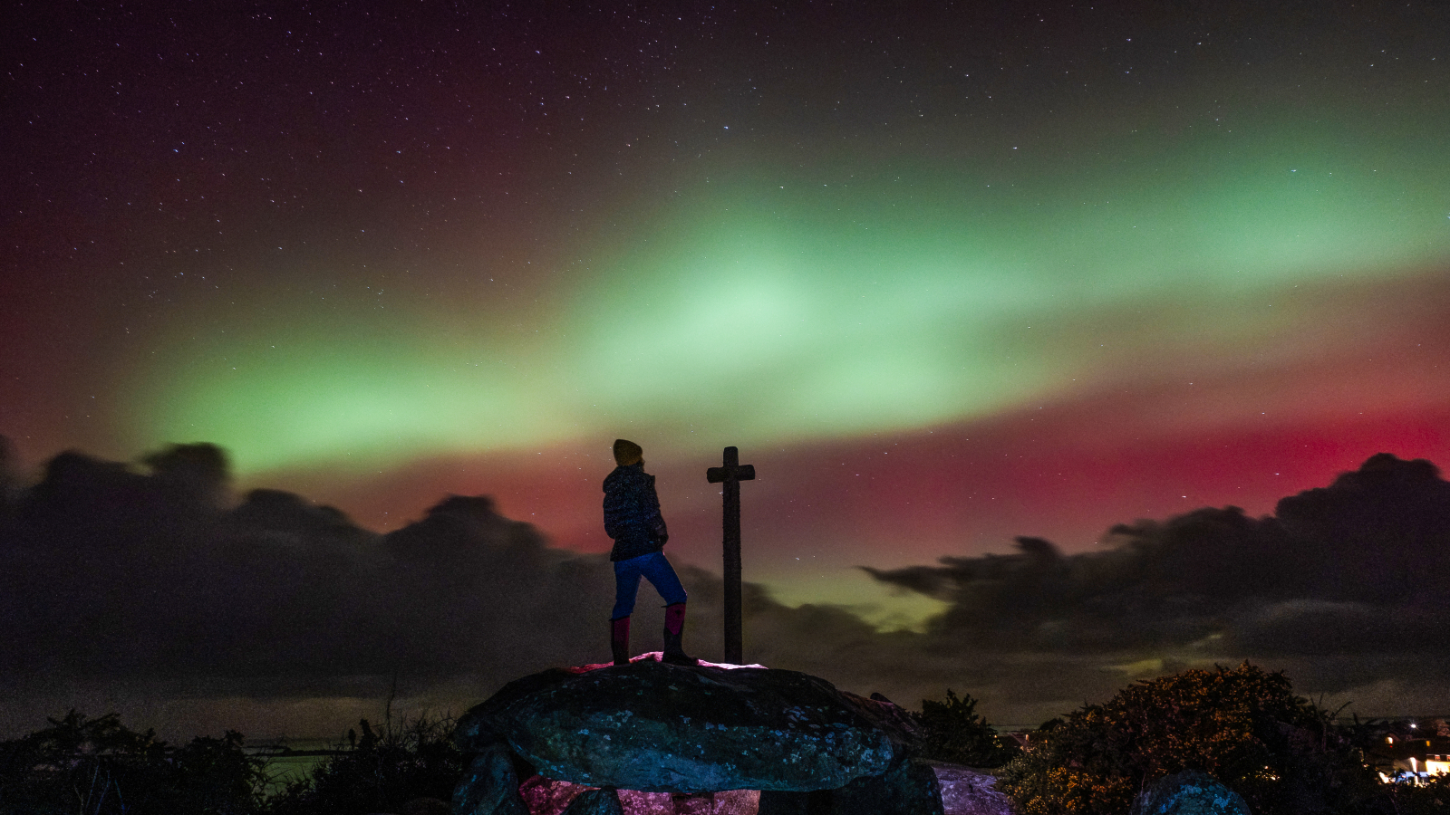Photo of person stood in front of green auroras in France