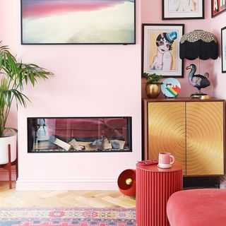 pink living room with fireplace and gold cabinet