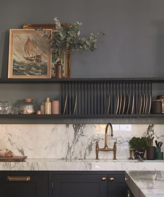 Dark kitchen with marble countertops and decorated display shelves