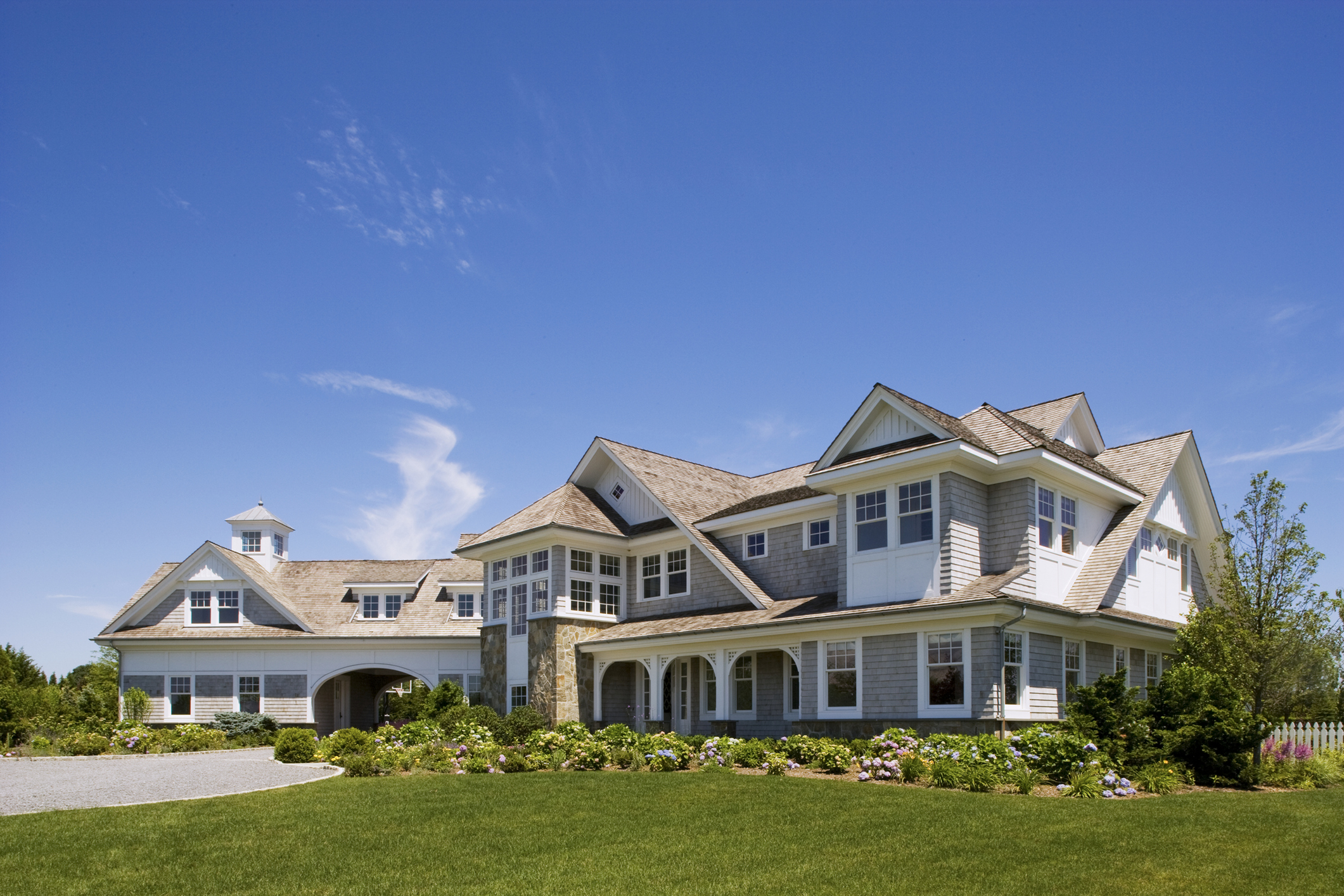Front exterior of a large private home and estate in the Hampton&#039;s on a beautiful summer day.