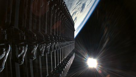 a row of rectangular satellites seen against the blackness of space and the curvature of earth below them