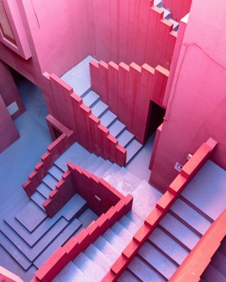 View from above of pink and purple, optical illusion style walls and stairs running across multiple levels at La Muralla Roja by Ricardo Bofill in Calp, Spain