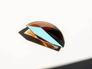 a semi circular glass sculpture by John Hogan in amber coloured glass with a blue profile