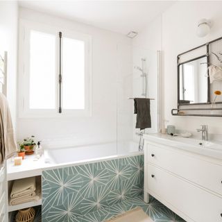 white bathroom with sea green 'lily pad' tiles on the bath panel and continued onto the floor