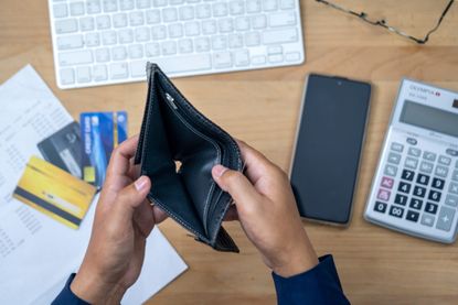 Close up of hand opening empty wallet over calculator