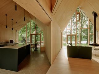 the lake house, a timber structure in a forest, made up of a cluster of volumes with pitched roofs