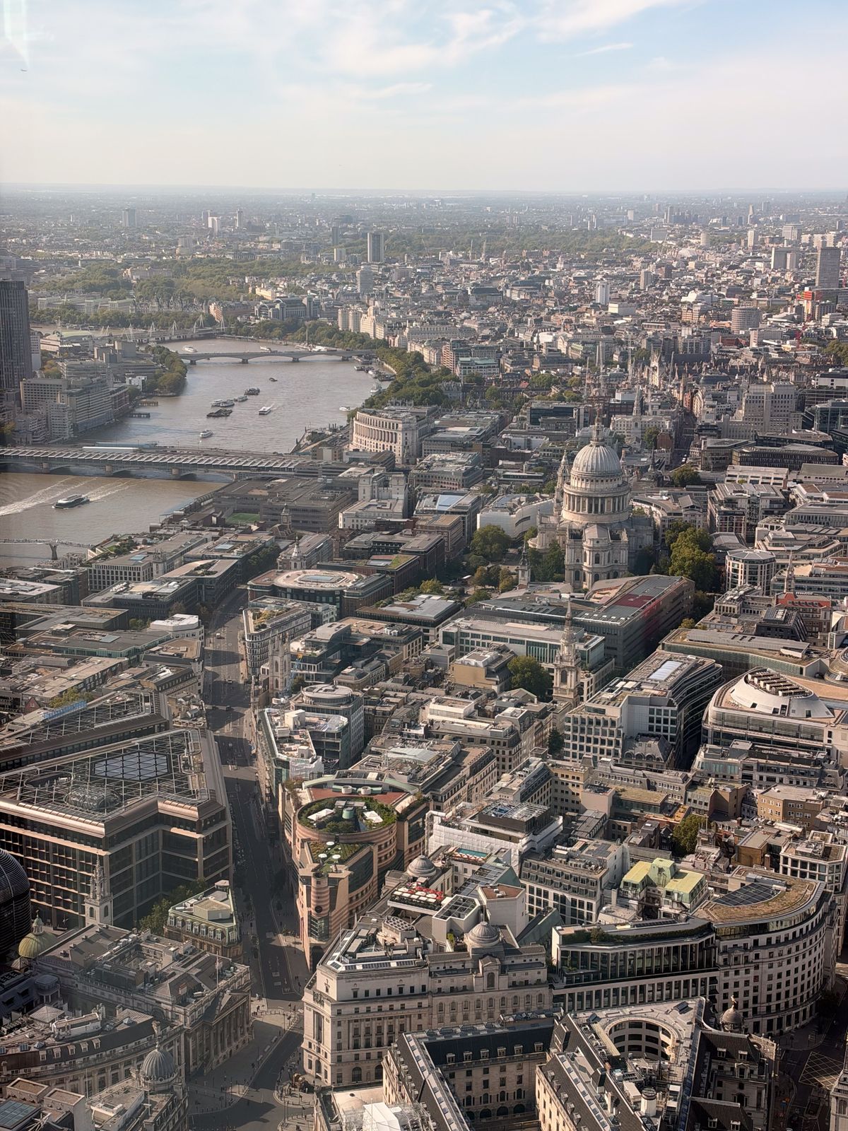 High aerial view across central London, with St Paul&rsquo;s Cathedral and the River Thames visible among dense city buildings.