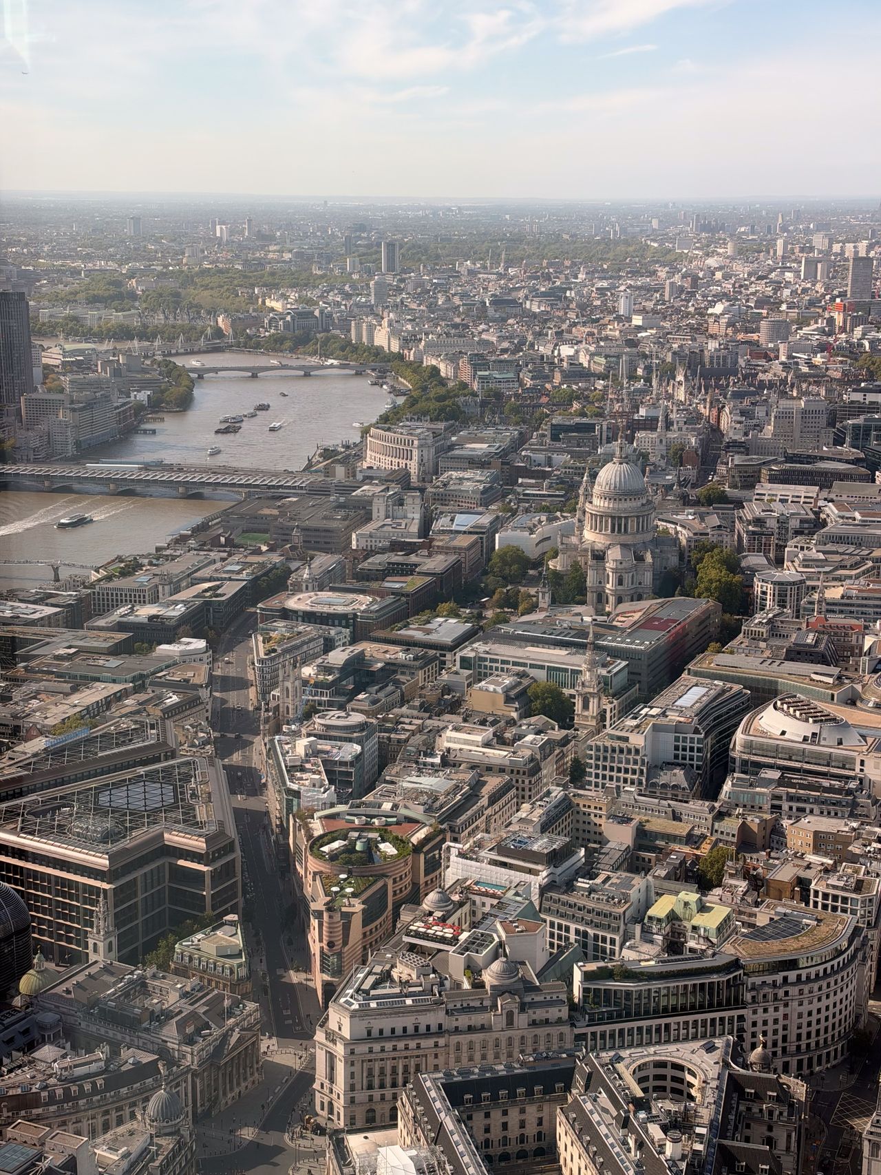 High aerial view across central London, with St Paul&rsquo;s Cathedral and the River Thames visible among dense city buildings.