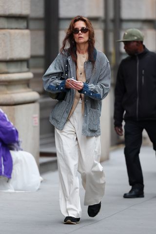 Katie Holmes wearing a navy-and-white barn jacket with camel Lafayette 148 vest and white trousers in New York City May 2024