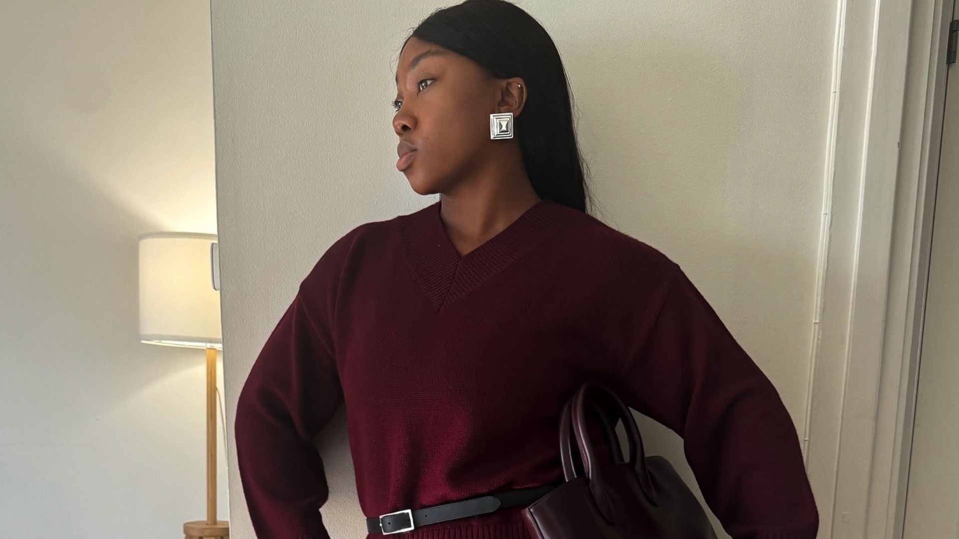 Influencer @nnennaechem wears a v-neck burgundy jumper with a black balloon skirt and mesh ballet flats.