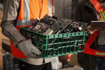 Male and female recycling coworkers holding digital tablet and plastic box full of mother boards.