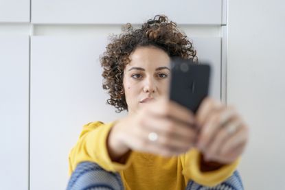 Social media filters: A woman taking a selfie looks at her phone sadly