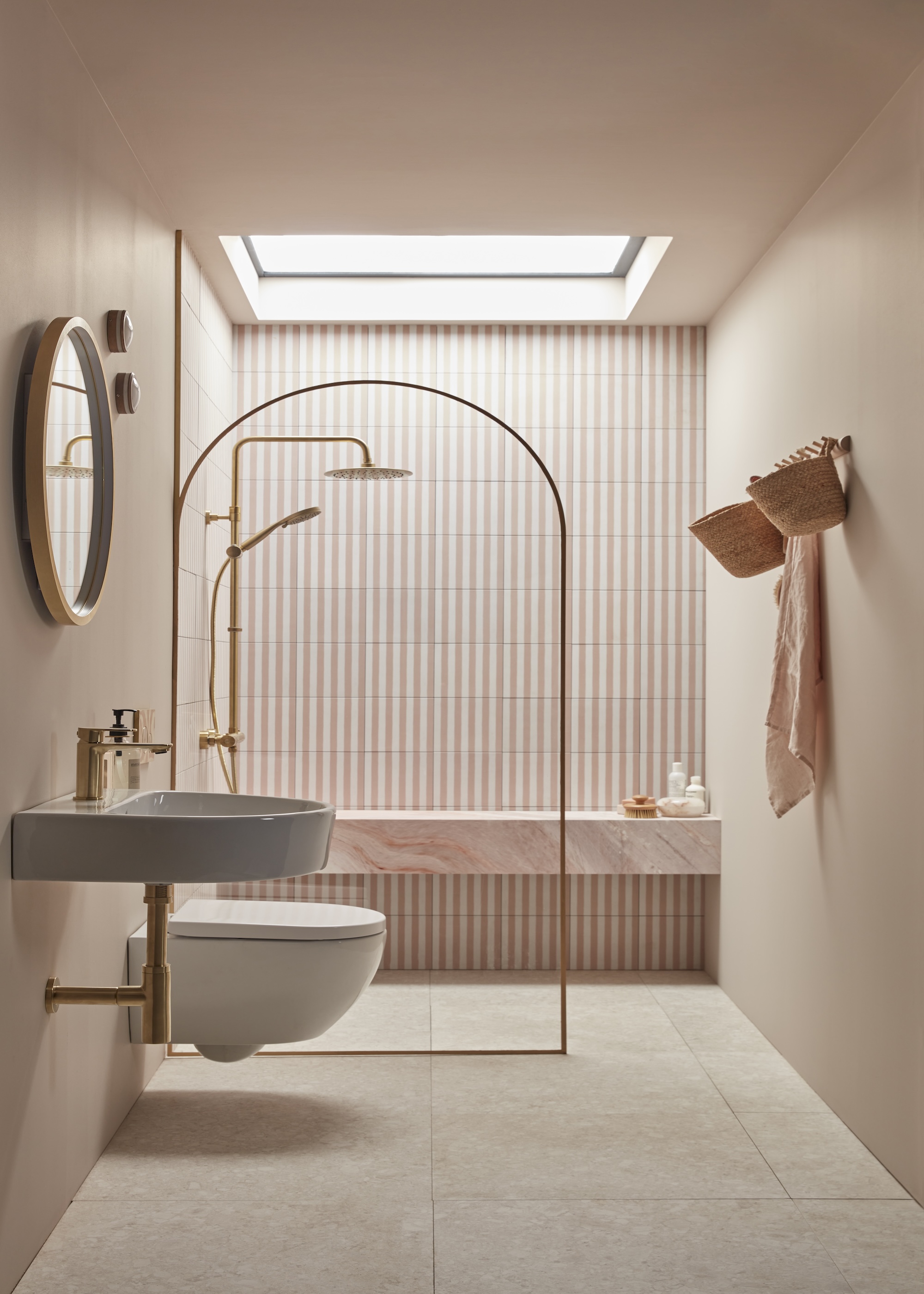 A bathroom with thin tiles and a split glass between the shower and toilet area