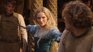 Morfydd Clark (Galadriel) holds blades to two men in The Rings of Power