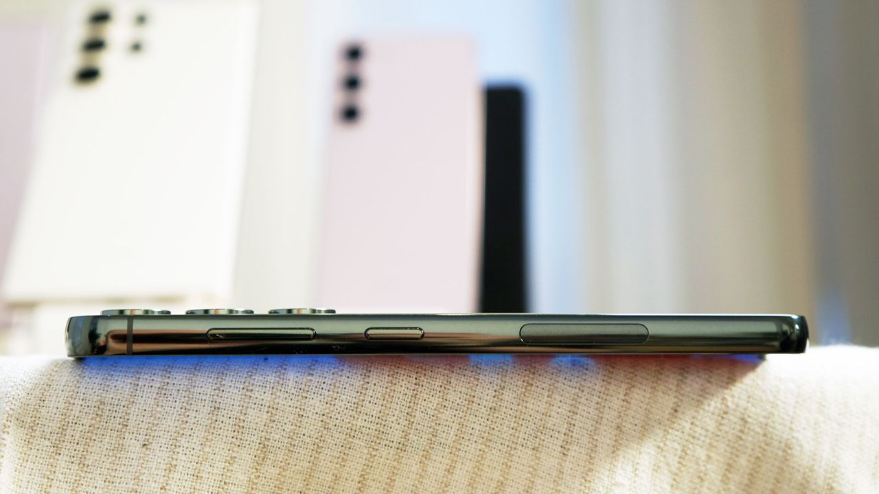 A side view of the Samsung Galaxy S23 Plus in dark green. Other Samsung Galaxy S23 phones are visible in the background