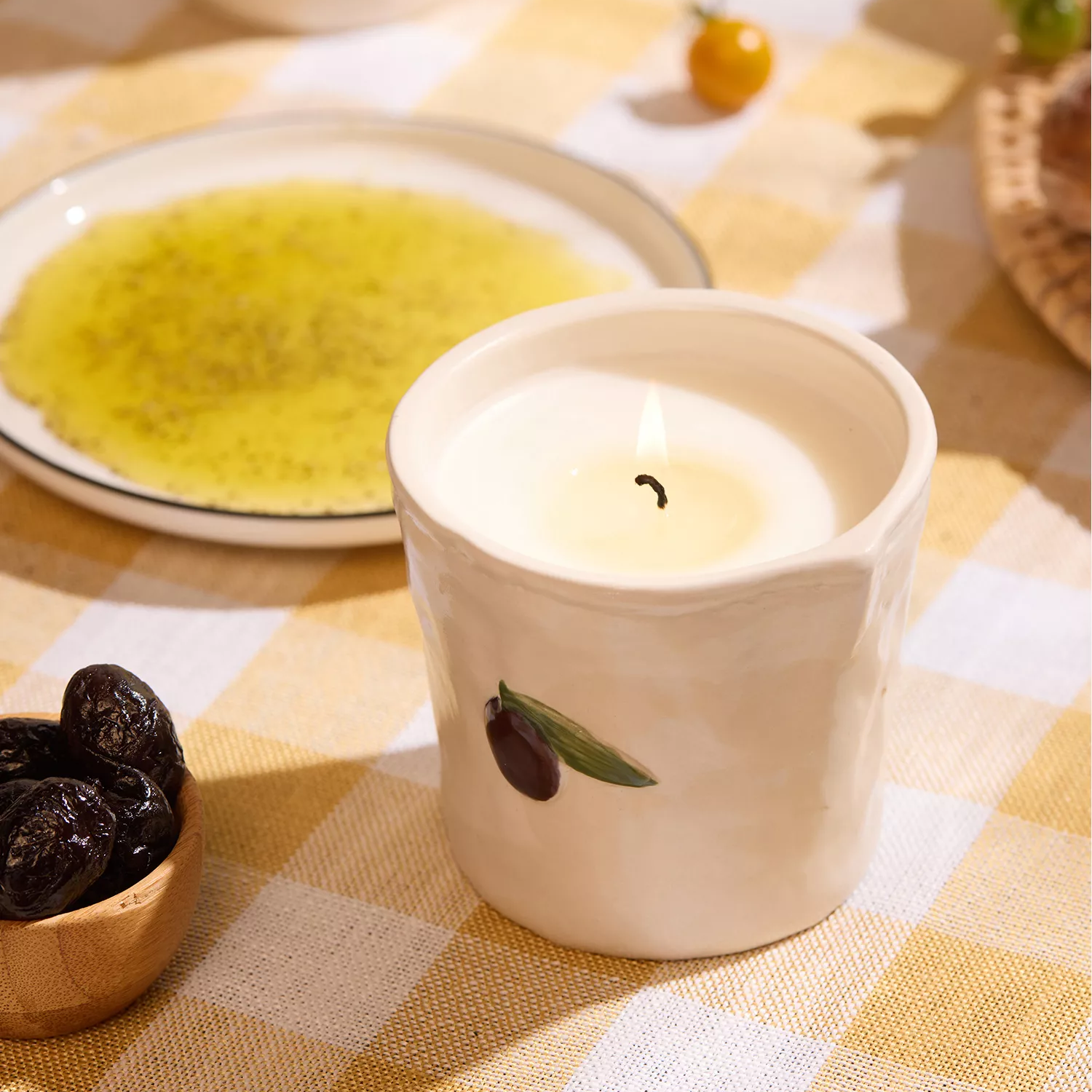 A ceramic candle by a plate of olive oil