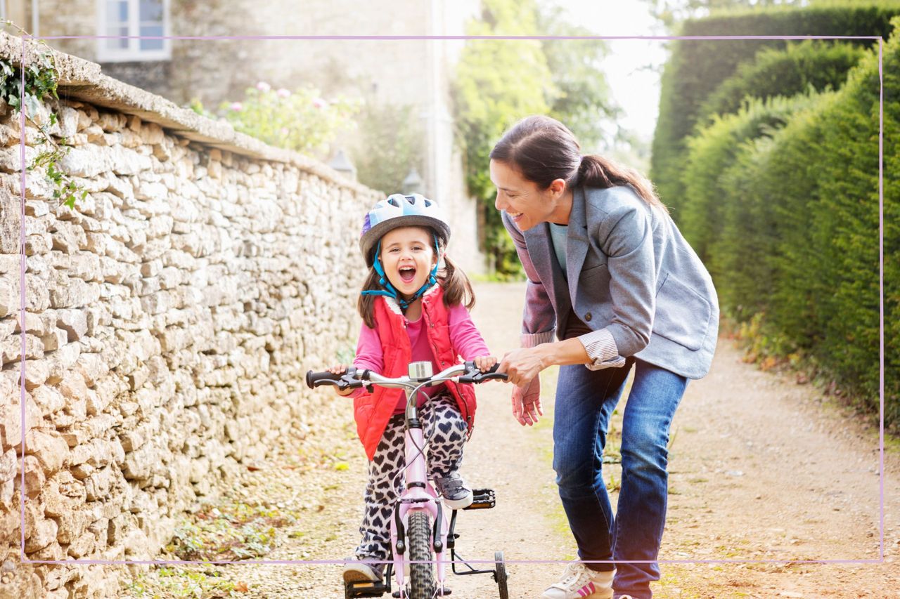 Mother holding to child while she rides her bicycle 