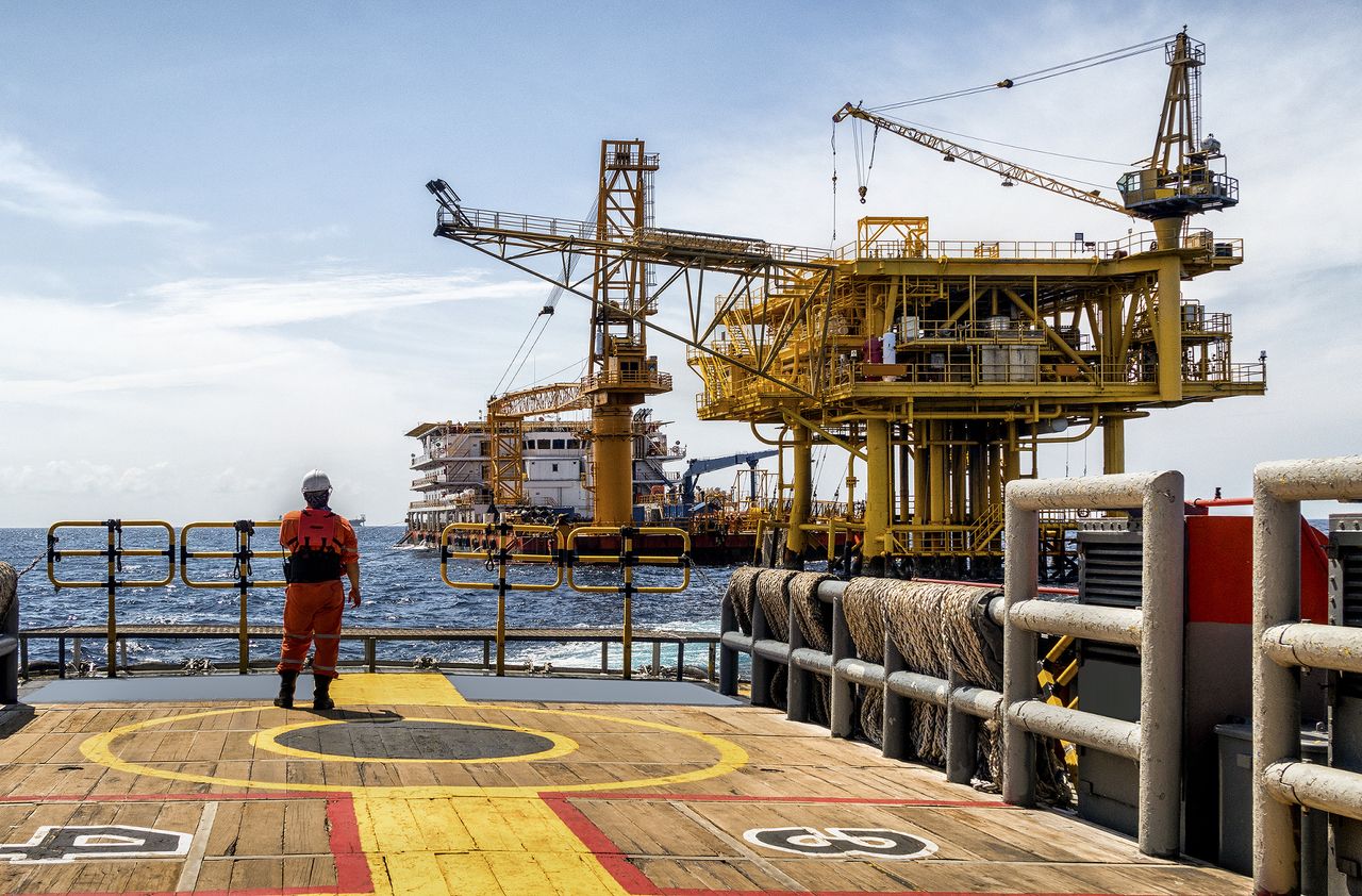 Worker on the boat look at Oil and gas industrial platform in the gulf or the sea, The world energy of oil and gas company, Offshore oil and rig construction. Industry concept.