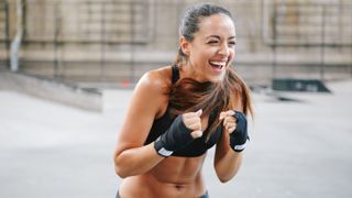 What does cardio do to your body?? Image shows Young woman boxing in urban setting