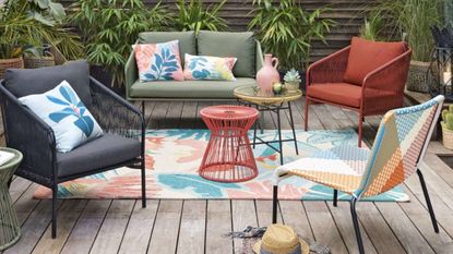 A colourful patterned outdoor rug on decking with contemporary garden furniture